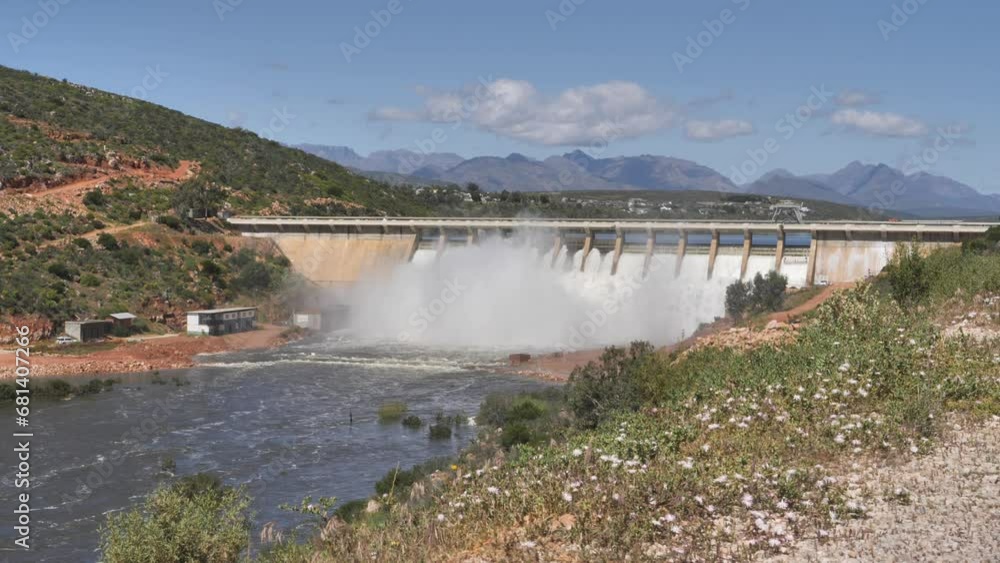 Water rushes over Clanwilliam Dam wall and the weir downstream. Cederberg Mountains behind Water rushes over Clanwilliam Dam wall and the weir downstream. Cederberg Mountains behind