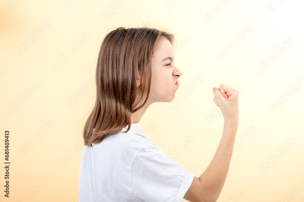 Teenager girl shows fist on yellow background isolated, side view. Teenager girl shows fist on yellow background isolated, side view.