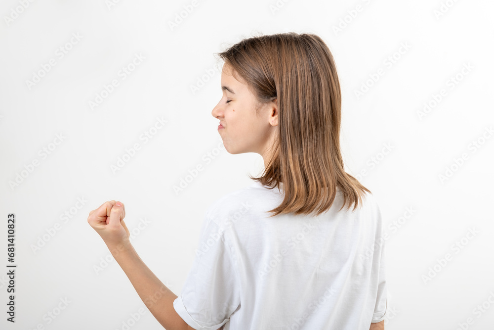 Teenager girl shows fist on white background isolated, side view. Teenager girl shows fist on white background isolated, side view.