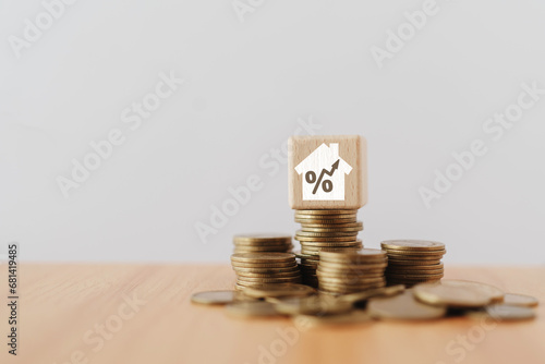 Home loan, mortgage and buy or sale  real estate concept. Wooden cube block with percent inside white house icon on stack of coins in soft focus including copy space