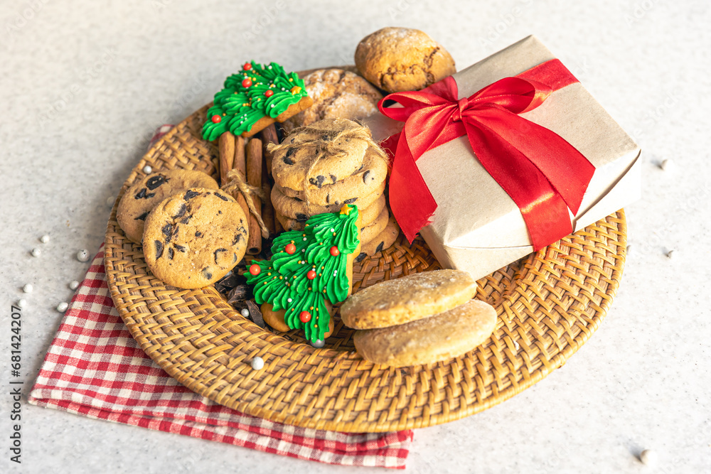 Festive Christmas cookies and gift box in a wicker plate on the kitchen table.
