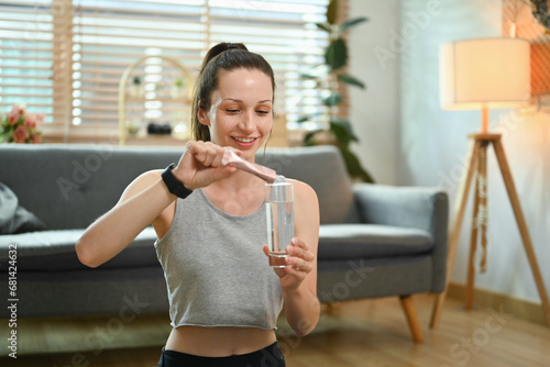 Sporty woman preparing healthy supplement, dissolving collagen powder in a glass of water