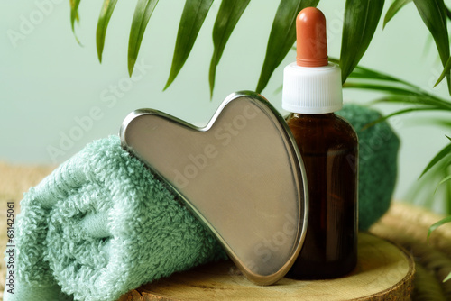 Steel gua sha with towel and oil in amber glass bottle photo