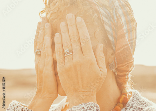 Close up portrait of female people hidden her eyes with hands to don't see around. Concept of surprise or scared woman. Worried about future woman in sunset atmosphere light and outdoors park photo