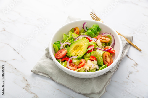 Healthy green salad with avocado, tomatoes, mozzarella and red onions