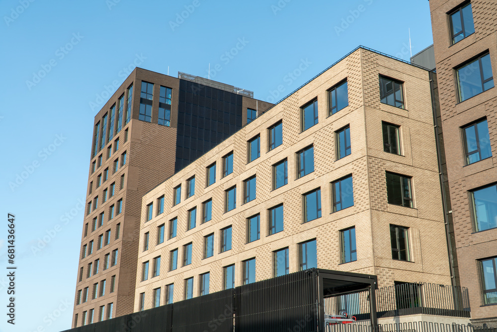 An example of minimalistic, cubic-shaped architecture with a view of the decorative decoration of the building facade. View of buildings from a low angle against a clear blue sky.