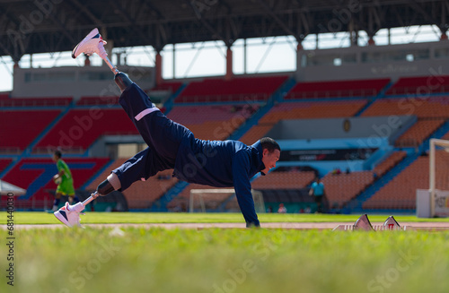 Disabled athletic man stretching and warming up before running on stadium track