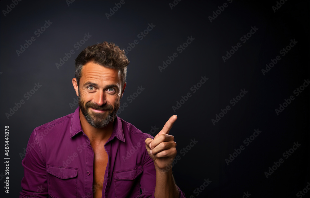 A man in a purple shirt pointing to the side, blank copy space background.