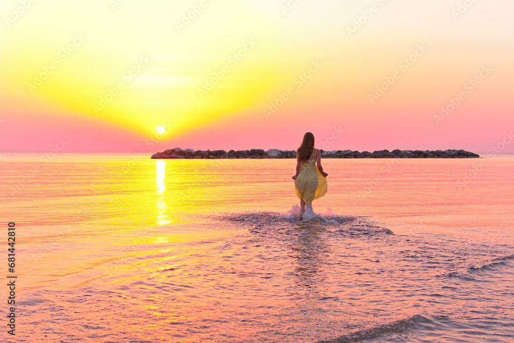 Beautiful woman walking in water wearing a yellow colorful dress