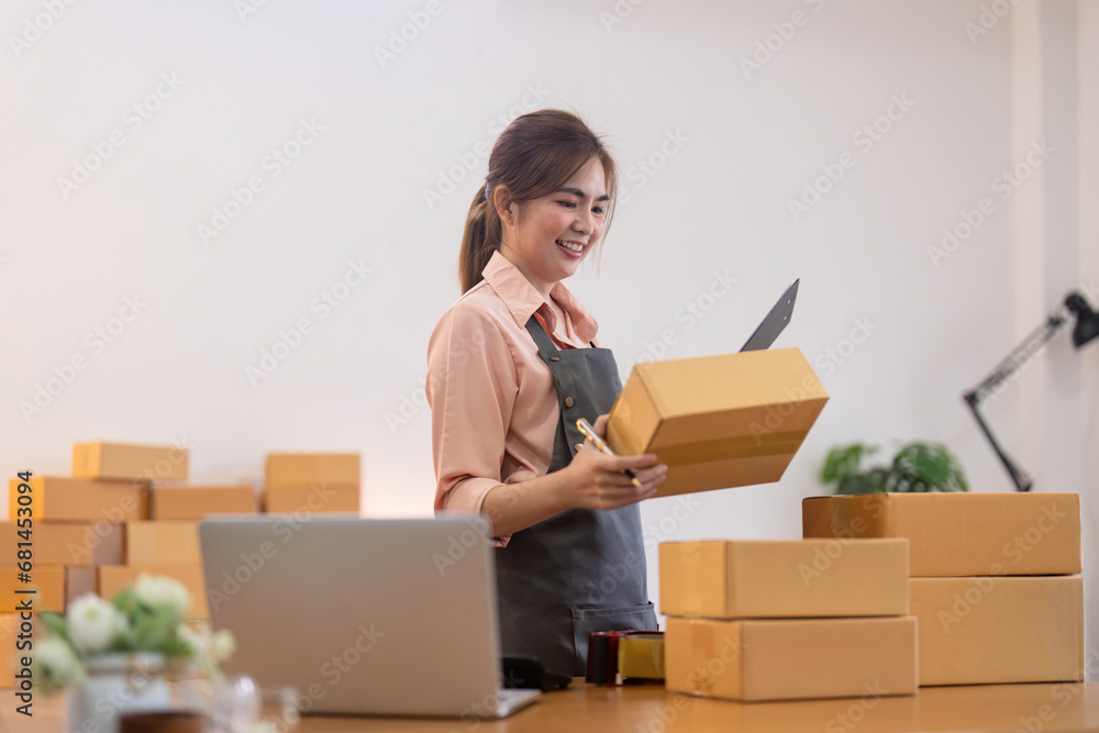Young woman working online ecommerce shopping at her shop. Young woman sell prepare parcel box of product for deliver to customer. Online selling, ecommerce. Selling products online Young woman working online ecommerce shopping at her shop. Young woman sell prepare parcel box of product for deliver to customer. Online selling, ecommerce. Selling products online