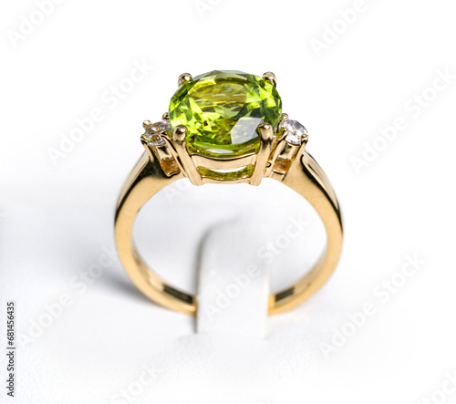 A vibrant peridot gemstone graces the center of a glossy, tarnish-resistant, yellow gold ring. The ring is accented with multiple pave-set  diamonds, sparkling exquisitely to complement the main stone photo