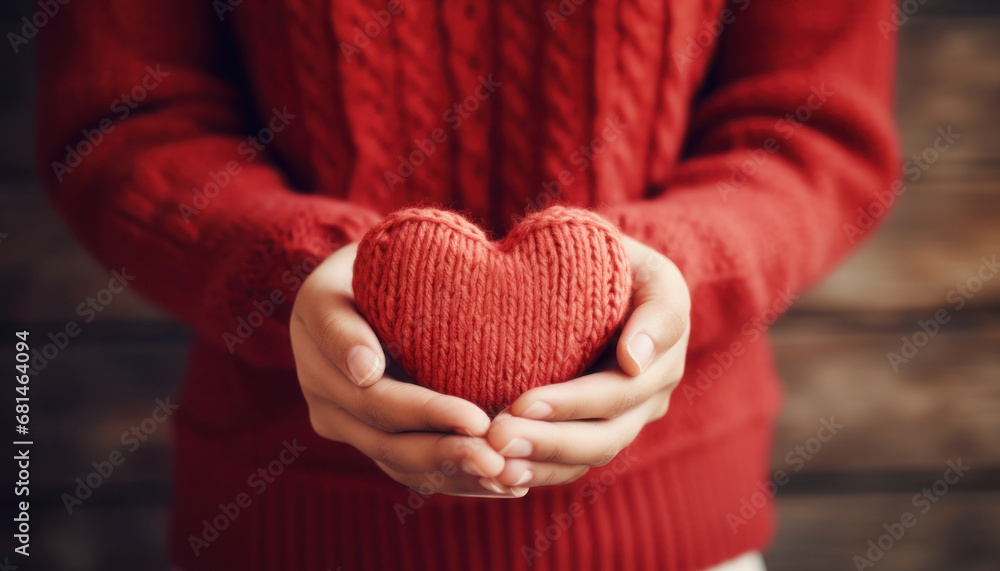 Female hands in a red sweater hold a heart knitted from red threads as a declaration of love on Valentine's Day Female hands in a red sweater hold a heart knitted from red threads as a declaration of love on Valentine's Day