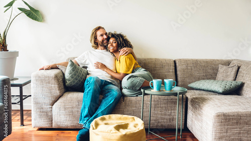 Cheerful multiracial couple sitting on sofa in the living room - Happy family moving in new home - Real estate and stylish furniture concept photo