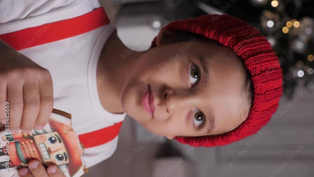 Merry Christmas kid. Portrait of a happy funny cute baby boy child one 6 years old in red clothes holding a Christmas gingerbread with a picture on it. New Year's Eve . Vertical