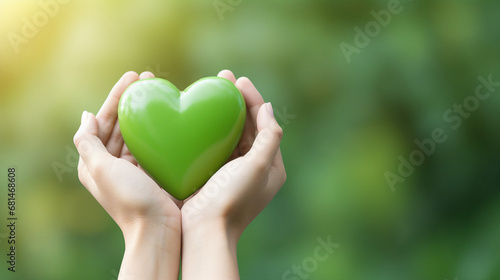 Hands holding a green heart with a blurred background