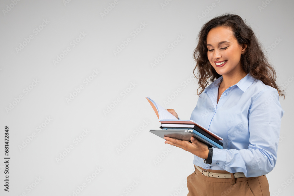 Smiling millennial european lady in formal wear with notebooks make notes with pen, planning day Smiling millennial european lady in formal wear with notebooks make notes with pen, planning day