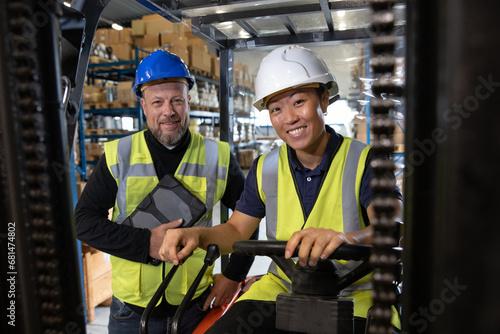 Portrait of employee in distribution warehouse being trained to operate a forklift truck