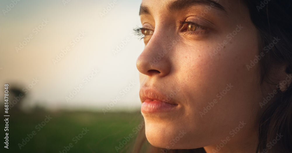 Attractive Young Female Standing Outdoors and Enjoying Nature Around. Smiling Brunette Girl with Natural Face Features and Green Eyes. Scenic Sunset Light and a Cinematic Rural Landscape. Close Up - obrazy, fototapety, plakaty 