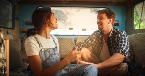 Young Beautiful Couple Relaxing in a Camper Trailer, Enjoying a Fun Conversation in a Cozy Motorhome. Camping Caravan Lifestyle, Adventure, Recreation, Nature Tourism and Relationship Concept