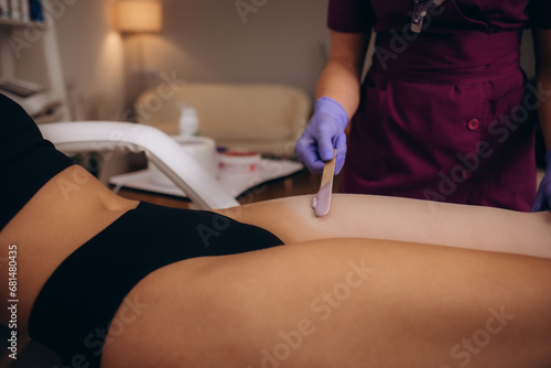Hair removal at spa studio. Woman legs wax with shugaring. Hot sugar. photo
