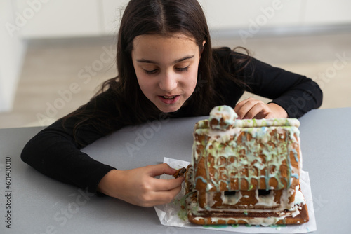 Fotografi Kids with gingerbread house, A teenage girl is eating a gingerbread house