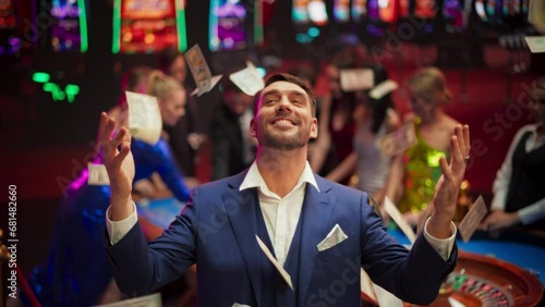 Portrait of an Excited Young Man Catching Money that is Flying From the Sky. Successful Gambler Won a Jackpot in a Casino. Concept of Gambling, Betting, Finance, Luxury and Success photo