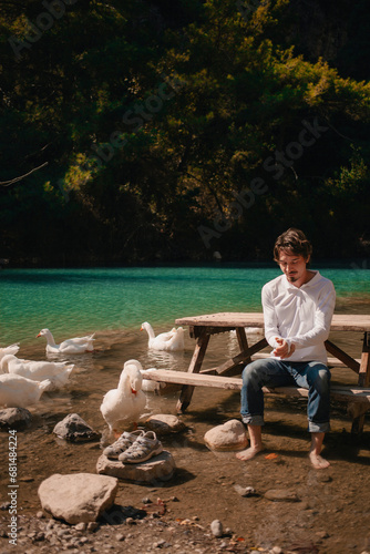 A man enjoys a vacation in the mountains on a lake in Turkey next to white geese. portrait