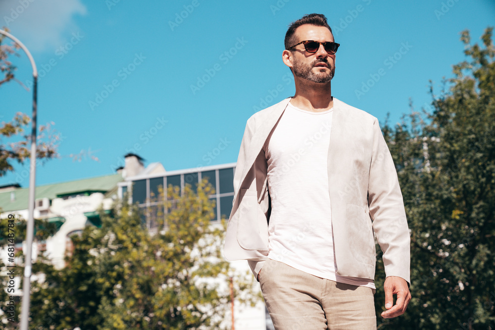 Portrait of handsome confident stylish hipster lambersexual model. Sexy modern man dressed in elegant suit. Fashion male posing in the street background in Europe city at sunset. In sunglasses Portrait of handsome confident stylish hipster lambersexual model. Sexy modern man dressed in elegant suit. Fashion male posing in the street background in Europe city at sunset. In sunglasses