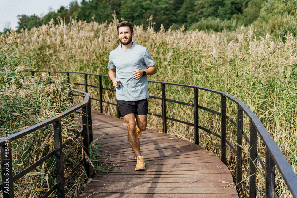 Healthy and active lifestyle. Running is a sporty slender young man in a T-shirt, shorts and sneakers. Running interval training alone in the park. Motivation for running and playing sports.