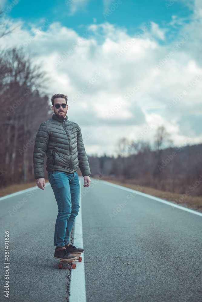 Cool hipster guy or man riding a longboard in the middle of the road in epic atmosphere. Freedom while riding a longboard, movie like setting. Long stretch of straight road, autumn setting. Cool hipster guy or man riding a longboard in the middle of the road in epic atmosphere. Freedom while riding a longboard, movie like setting. Long stretch of straight road, autumn setting.