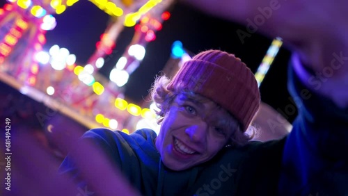 Creative teen man spinning camera performing contemporary dance at evening amusement park photo