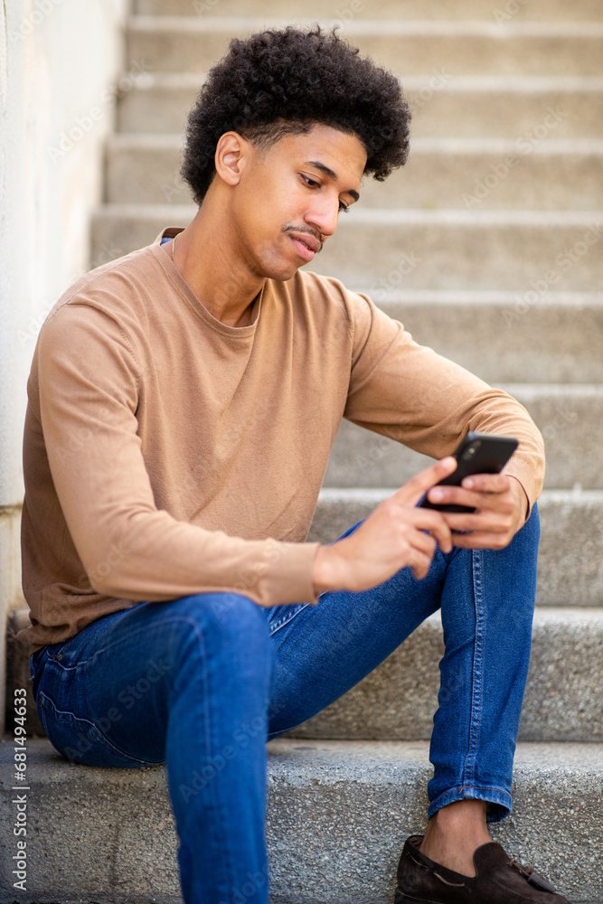 young hispanic man sitting on stairs with smart phone young hispanic man sitting on stairs with smart phone
