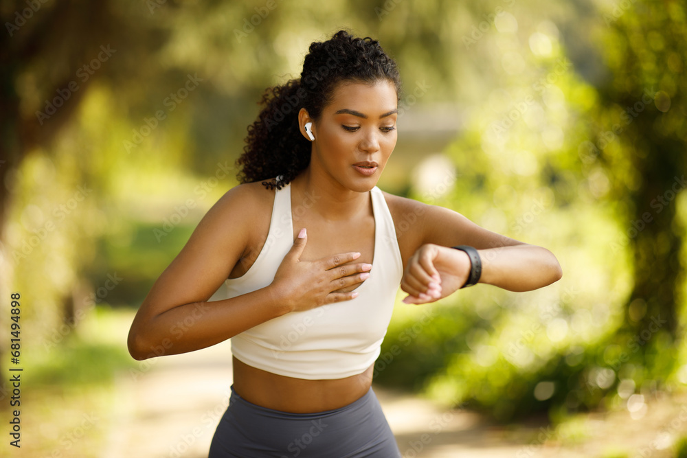 woman runner checking smartwatch pausing and breathing in run outdoors woman runner checking smartwatch pausing and breathing in run outdoors