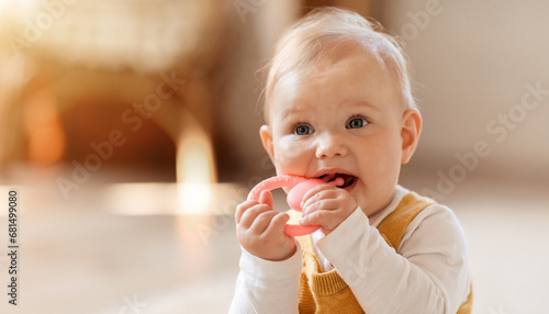 Fotografie Closeup of cute little baby sitting on floor, chewing teether