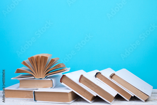 Open books, hardback colorful books on wooden table. blue background. Back to school. Copy space for text. Education business concept.