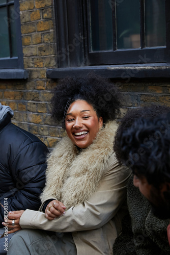 Group of stylish friends sitting outside in their coats and chatting. Concept of gen z, fashion and self expression.