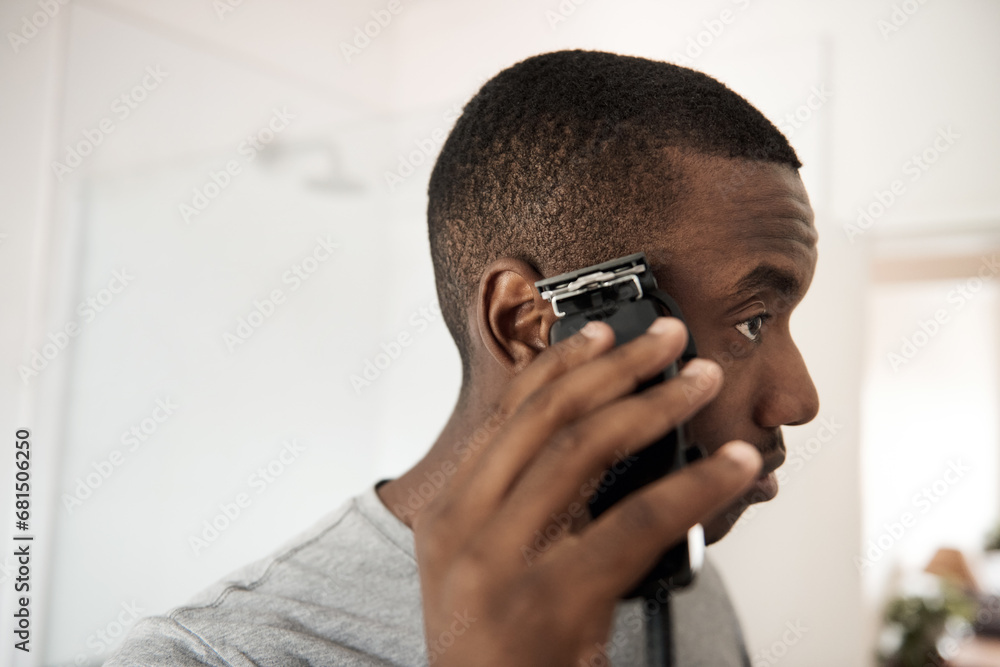 Young African man trimming his hair in his bathroom - obrazy, fototapety, plakaty 