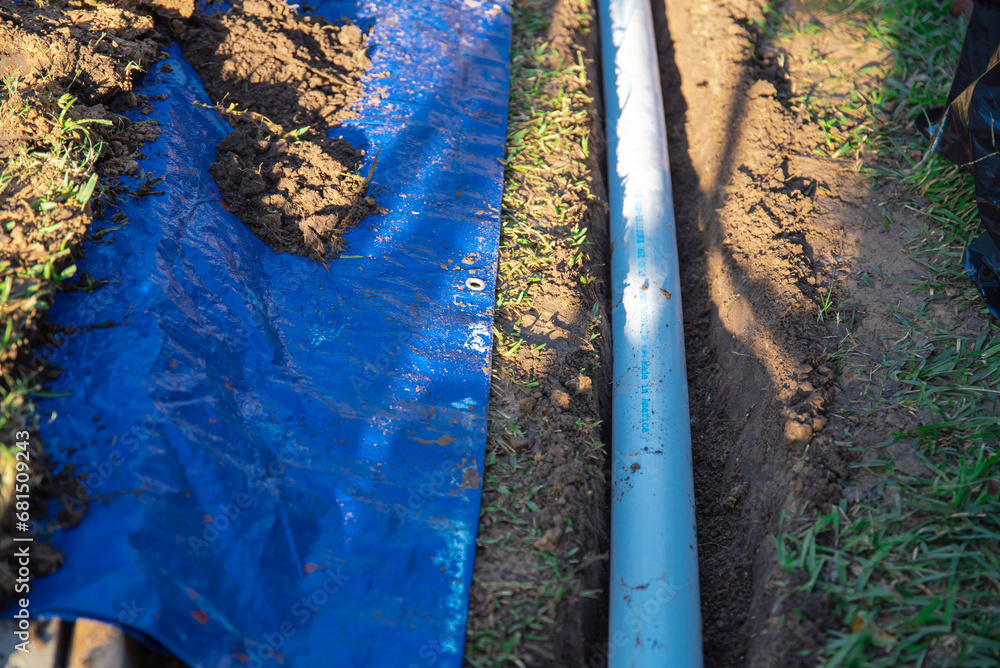 Underground PVC pipe buried in the trench installation, blue tarp with