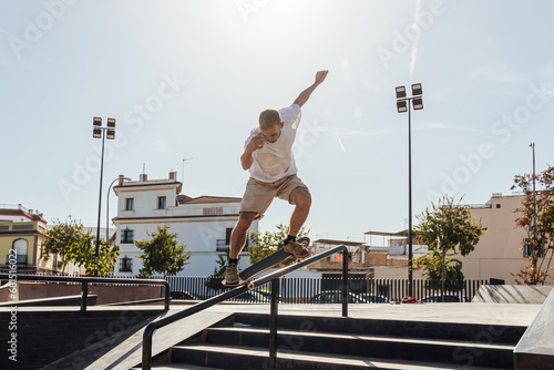 Energetic man riding skateboard on rail in skate park