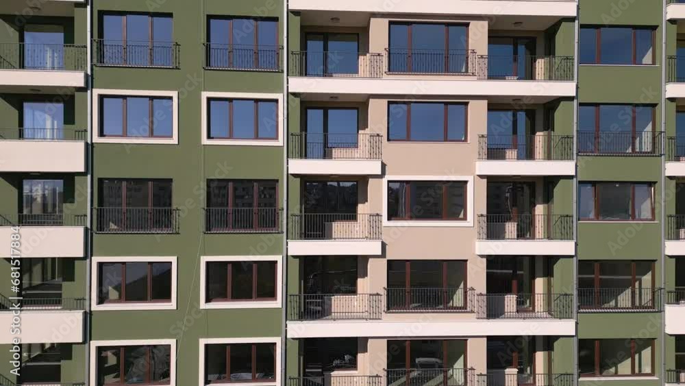 Drone flight along the facade of a modern apartment building under construction surrounded by scaffolding Drone flight along the facade of a modern apartment building under construction surrounded by scaffolding