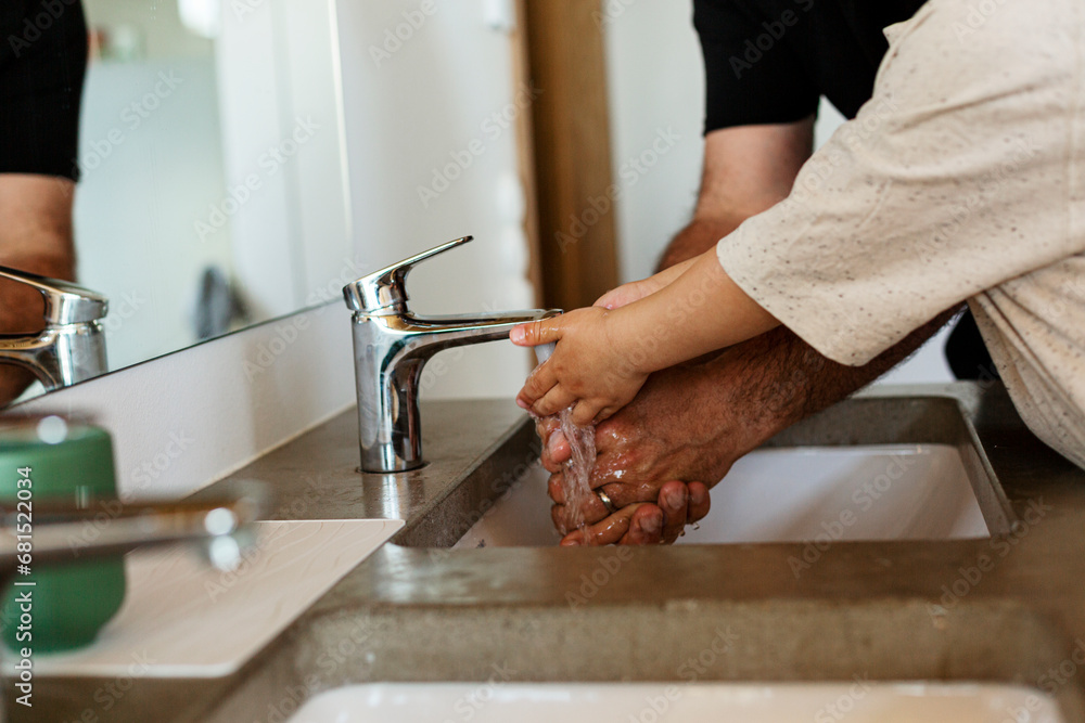 Mid section of father and child washing hands Mid section of father and child washing hands