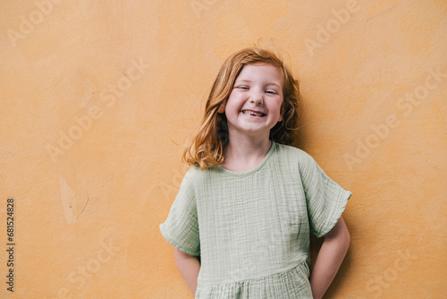 Red-haired girl smiling against wall photo