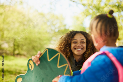 Smiling female teacher taking care of girl at playground photo