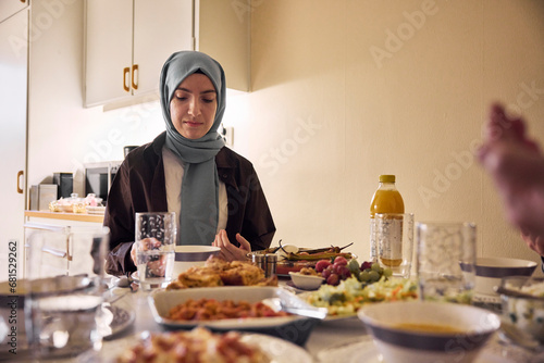 Woman in headscarf praying before meal