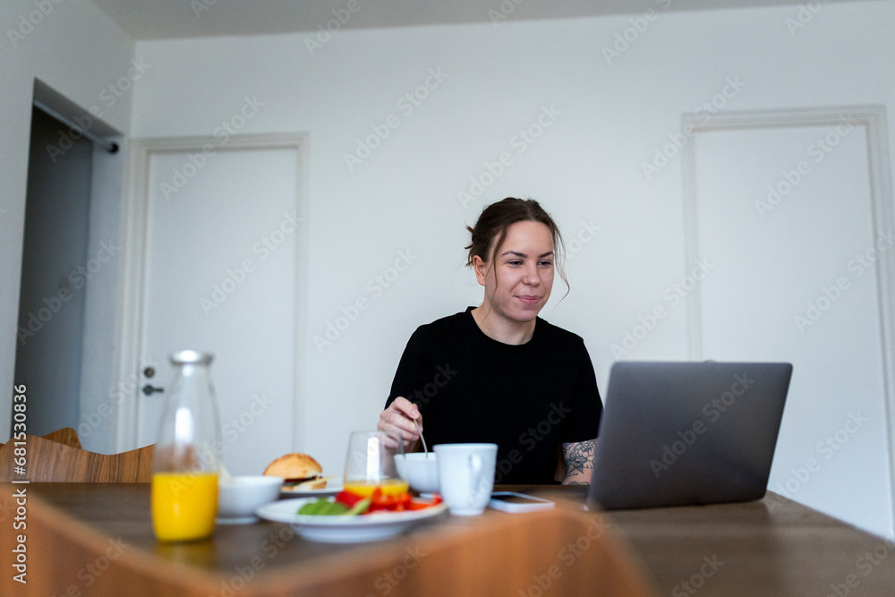 Young woman using laptop while telecommuting at dining table Young woman using laptop while telecommuting at dining table