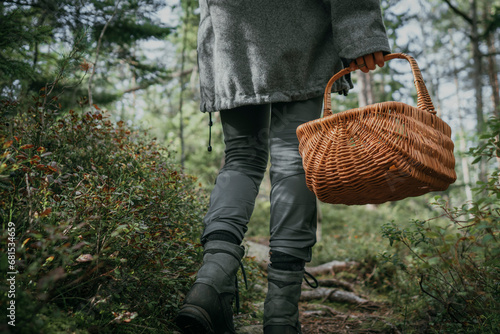 Low section of woman carrying wicker basket while walking by plant