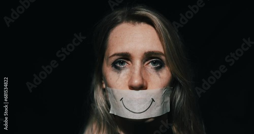 abuse and domestic violence. sad depressed woman hide her mouth behind fake drawn smile on paper tape. depression and mental health photo