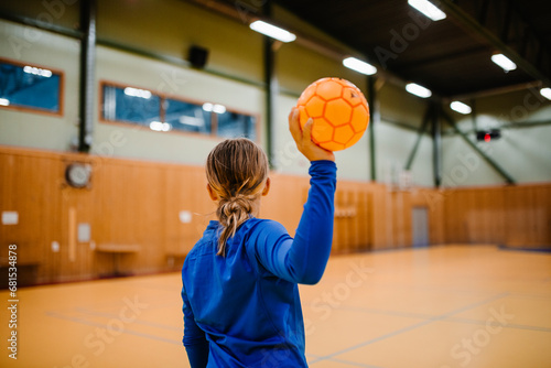 Rear view of girl holding handball in sports court photo