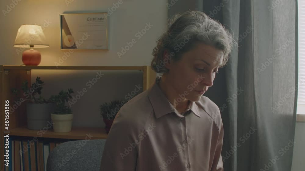 Zoom in shot of mature female doctor sitting in clinic and using laptop while examining health of patient Zoom in shot of mature female doctor sitting in clinic and using laptop while examining health of patient
