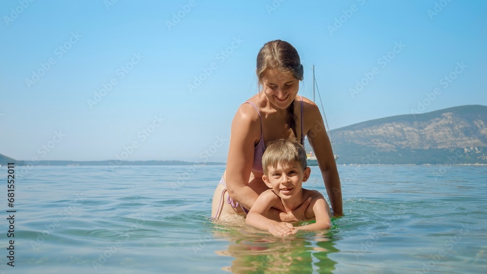 Little boy learning swimming in the sea with happy mother. Family holiday, vacation and fun summertime of children and parents.